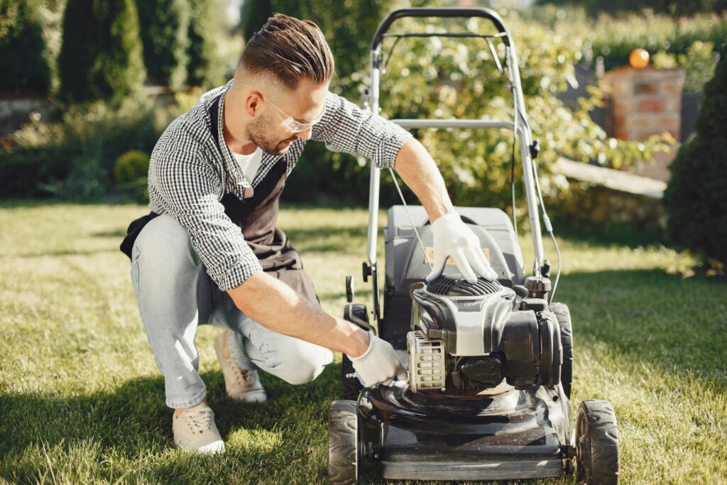 Man repairs lawnmover in a backyard